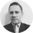 Portret czarno-biały mężczyzny w garniturze i krawatcie na szarym tle