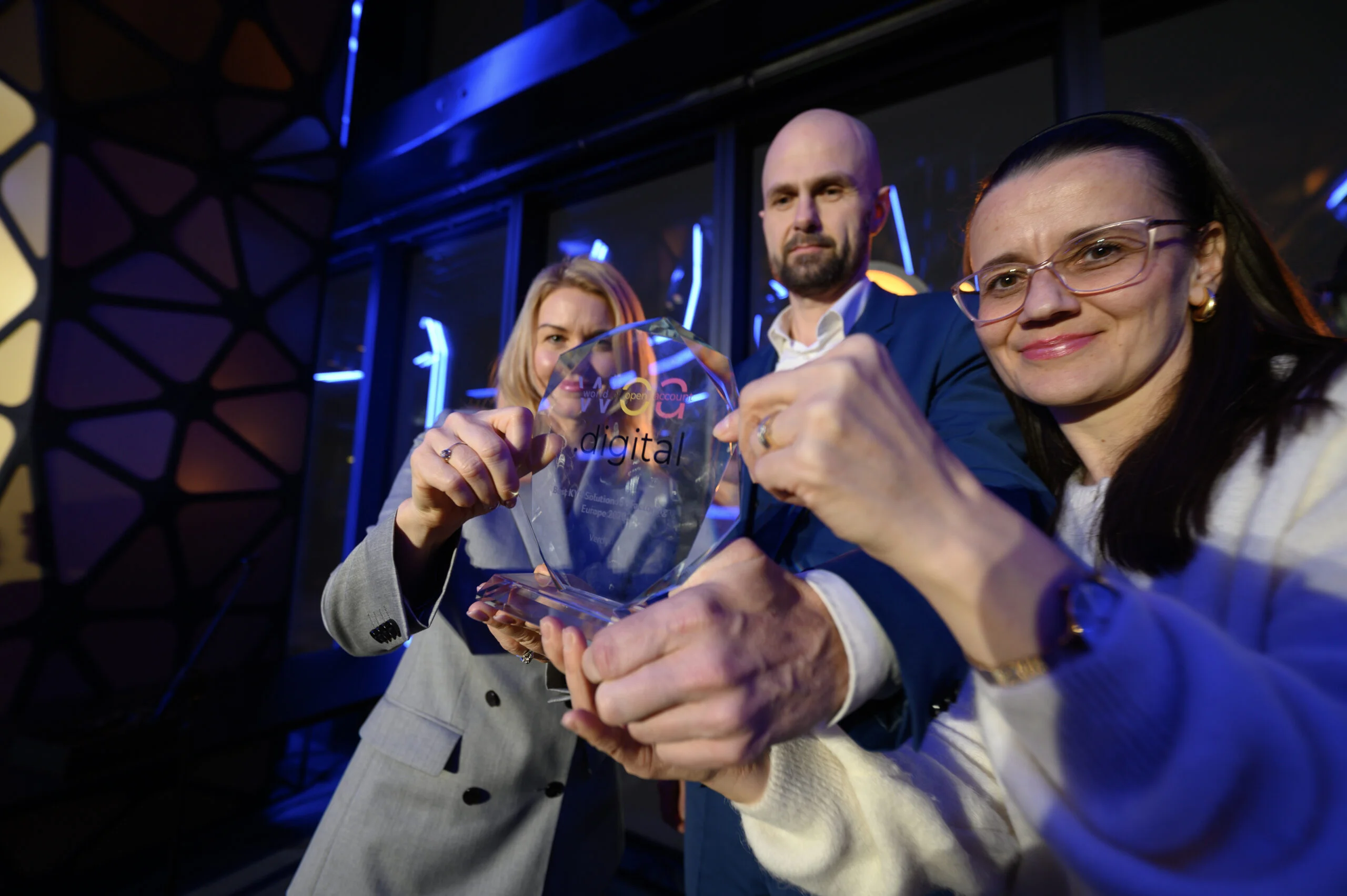 Zespół Vercly prezentuje nagrodę w nowoczesnym biurze z niebieskim oświetleniem