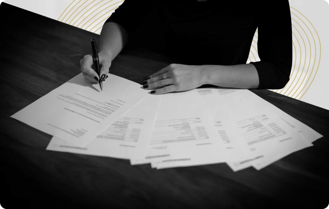 Osoba podpisująca dokumenty compliance przy biurku, czarno-białe zdjęcie